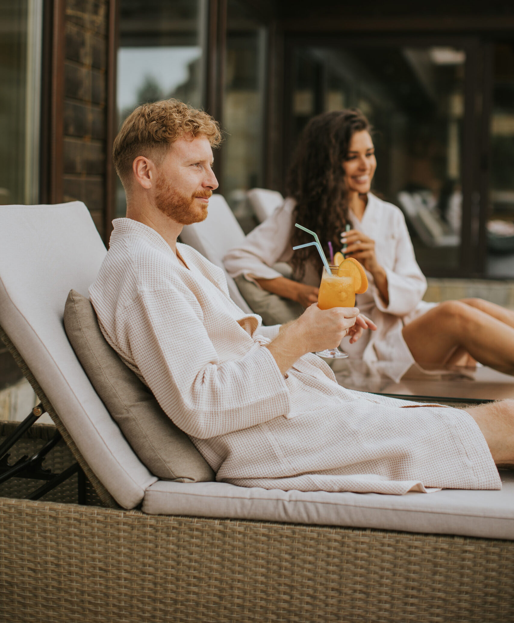 Young couple relaxing on beds and drinking fresh orange juice on