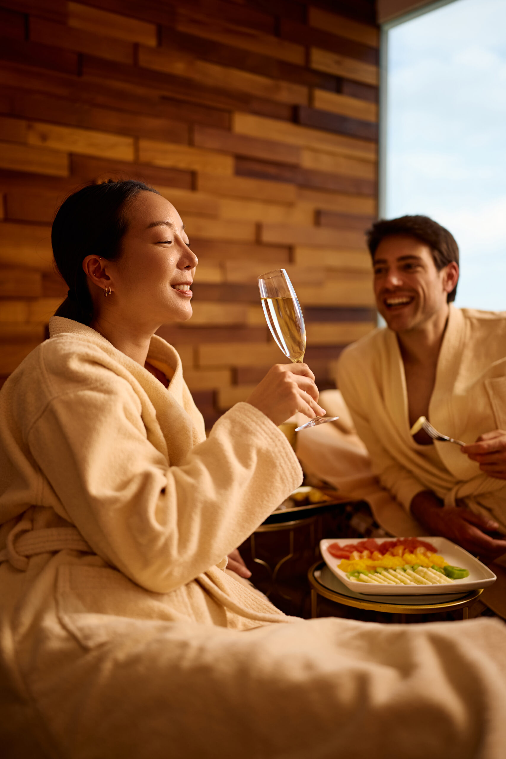 Happy woman drinking champagne while spending a day at the spa with her boyfriend.